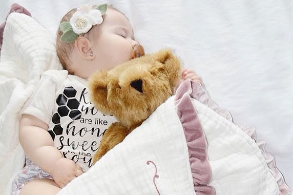 An image of a baby laying with a 15-inch Baby Girl Bear