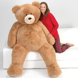 6' Giant Hunka Love Bear - Seated golden brown bear with a female model in red pajamas on a sofa image number 0