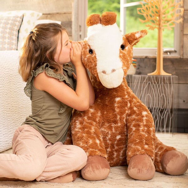3 1/2' Gentle Giant Giraffe - Three quarter view of seated soft giraffe in bedroom scene image number 0