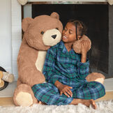 3 1/2' Gentle Giant Bear - Front view of seated brown bear with model in pjs image number 0