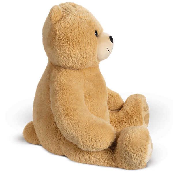 4' Boo The Loveable Big Teddy Bear - Side view of seated light butterscotch brown bear with ivory muzzle, smile and hear foot pads